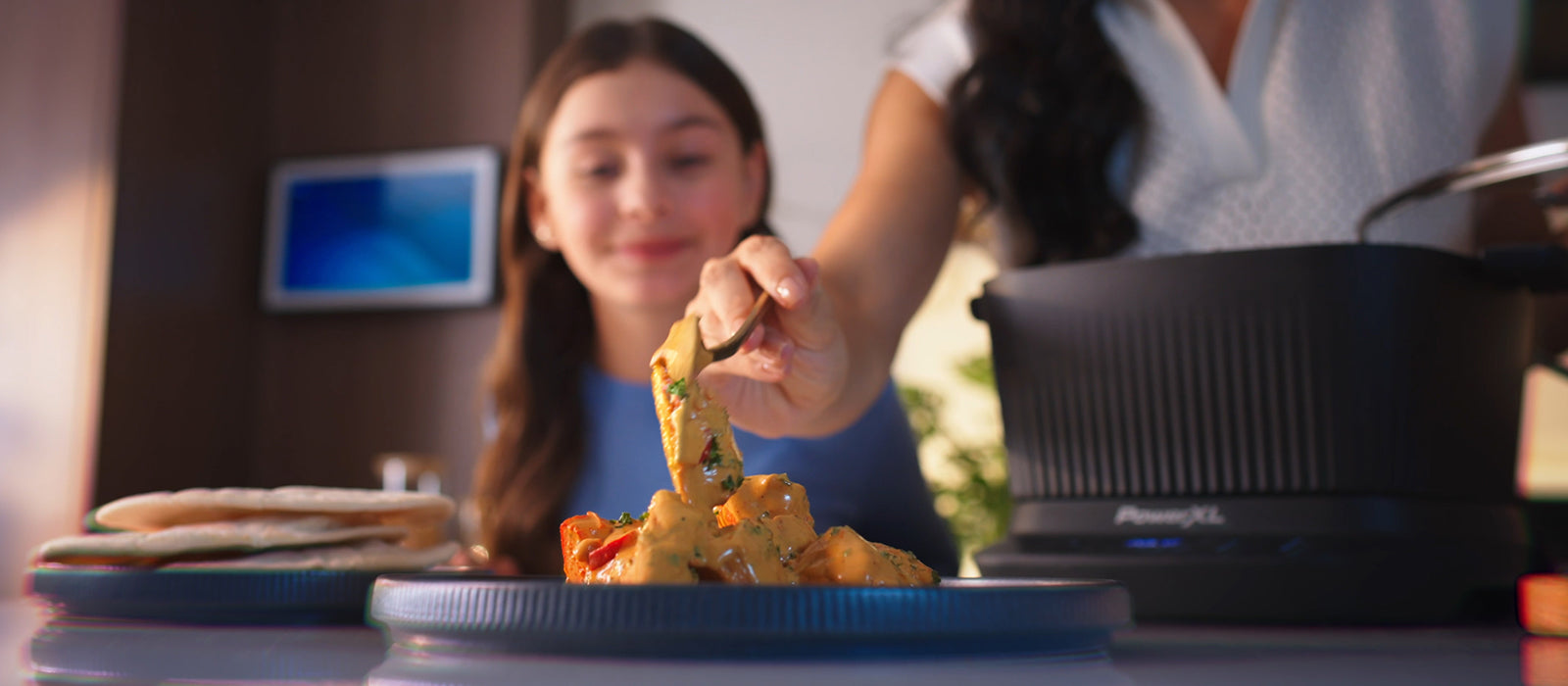 Person serving food from a Stirmax pot to a child in a kitchen setting
