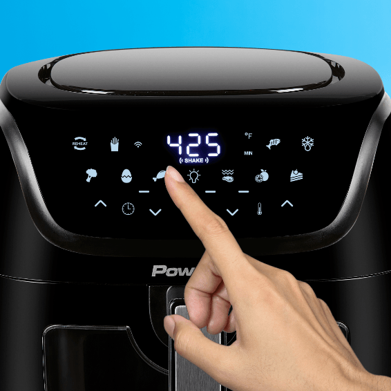 Hand pressing a button on aair fryer with a digital display against a blue background