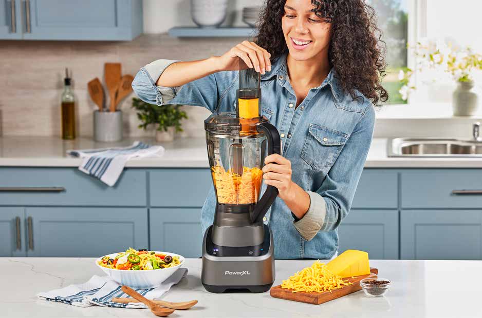 Woman using Sensimax blender in a kitchen with a salad and cheese on the counter.