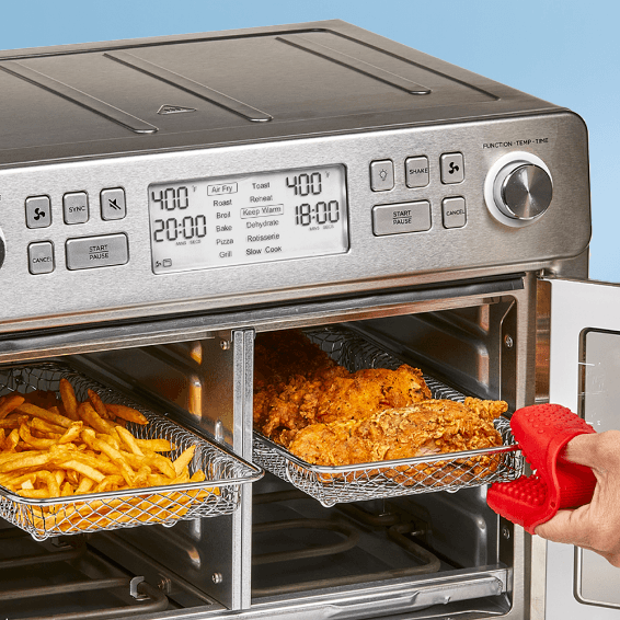 Multifunctional kitchen appliance with food items inside, including fries and chicken, on a blue background.