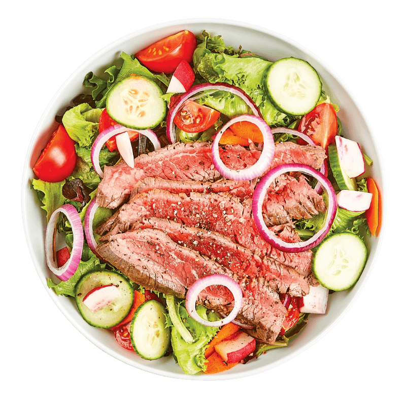 Salad with sliced beef, cucumbers, tomatoes, and onions in a white bowl on a transparent background