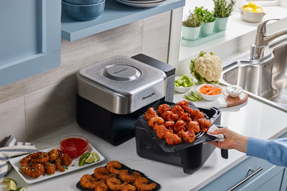 Power Air Fryer on a kitchen counter with cooked food and ingredients.