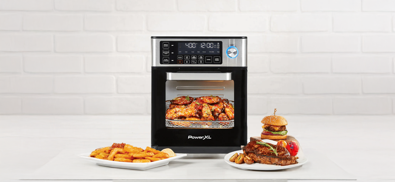 PowerXL Versachef Multicooker with food items on a white surface and tiled wall background